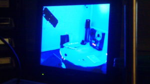 CCTV footage of a room. We see a table, a reel-to-reel tape player and scientific equipment
